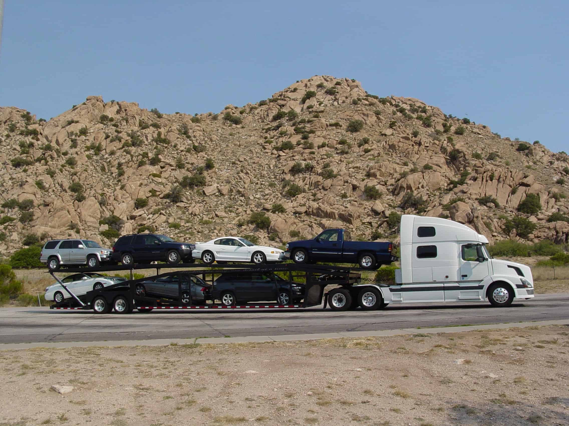 moving truck shipping cars on a desert road - Mayflower